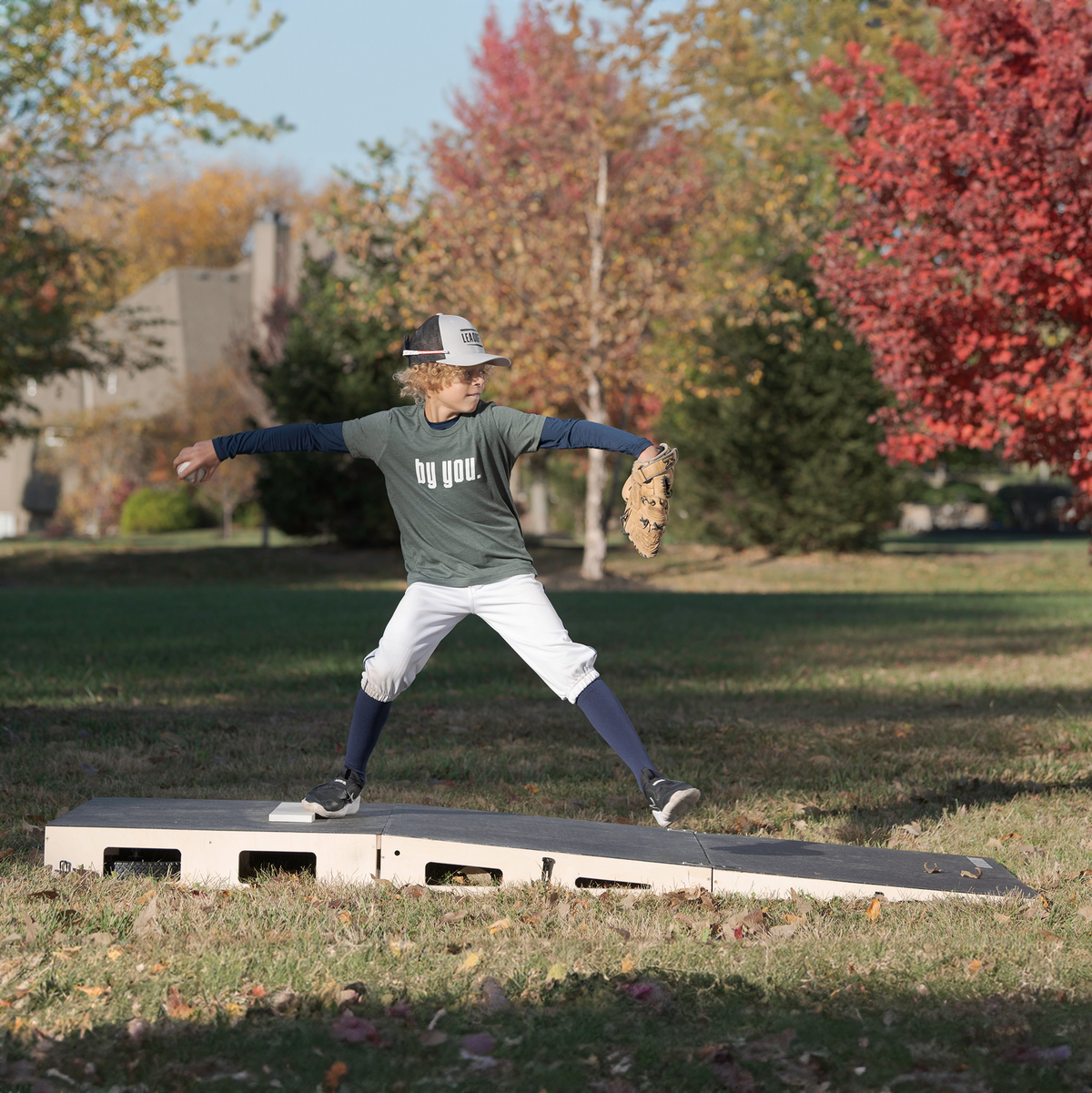 Young pitcher practicing on the FirstStrike Wheeled 6-Inch portable Pitching Mound in a park.